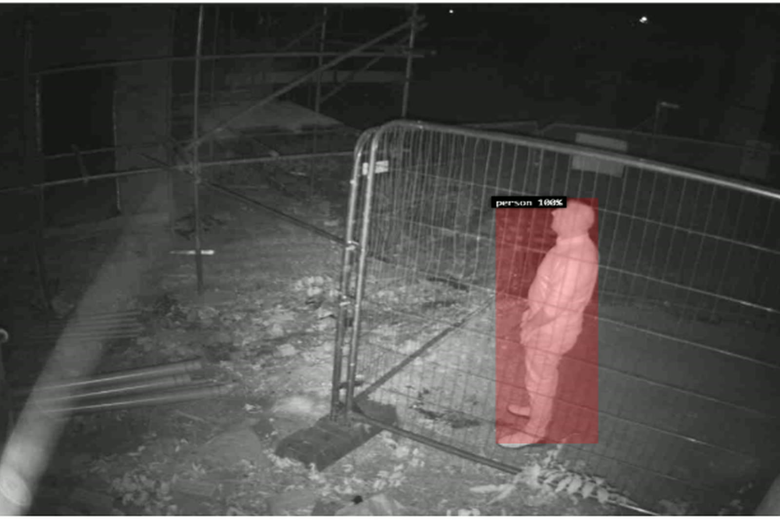 A night camera frame from an ACS site: a person at a site fence, boxed and labelled by the detection