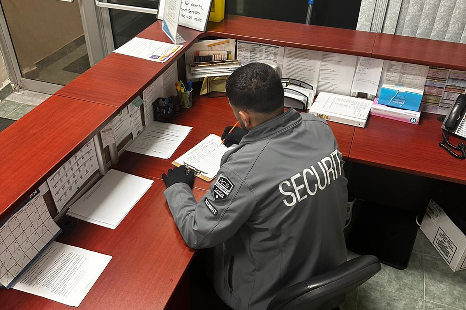An ACS officer at a front desk, writing up the shift log