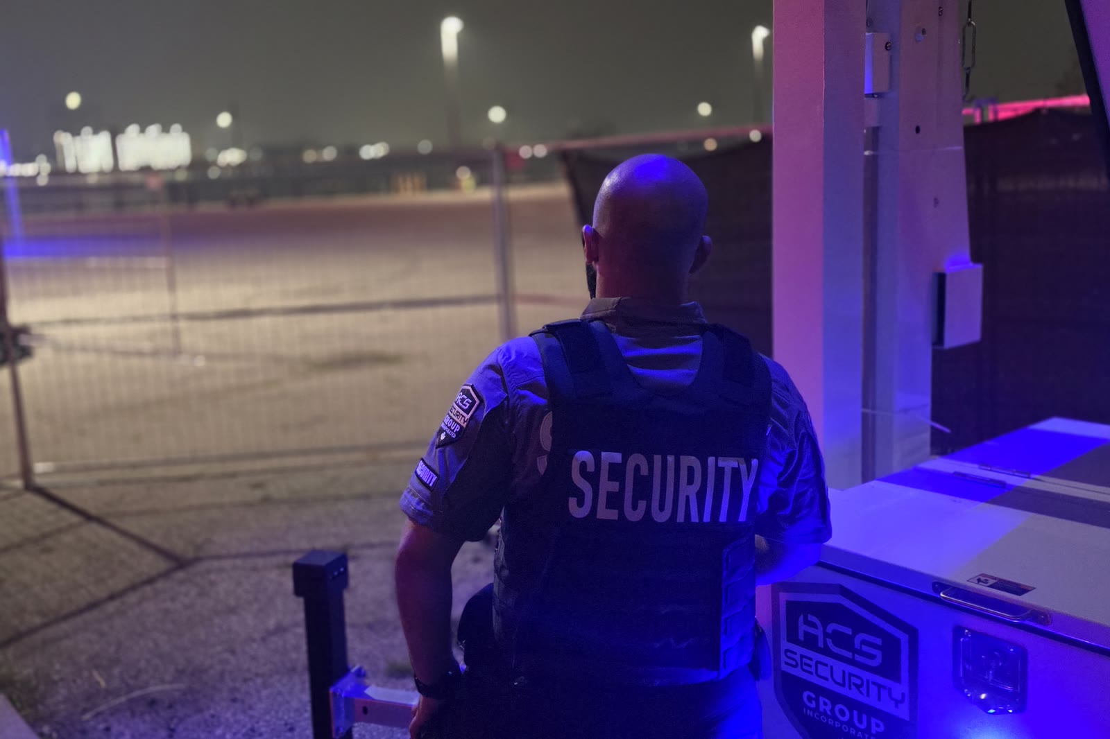 An ACS officer standing on a vehicle lot at night
