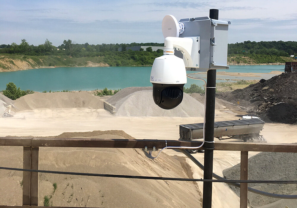 ACS pan-tilt-zoom camera on a post above a sand and gravel pit, with a quarry lake behind