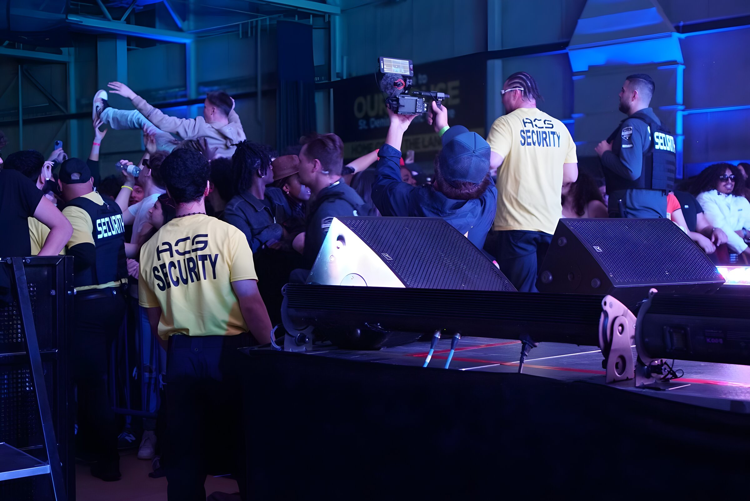 ACS crew holding the barricade at the front of an indoor concert
