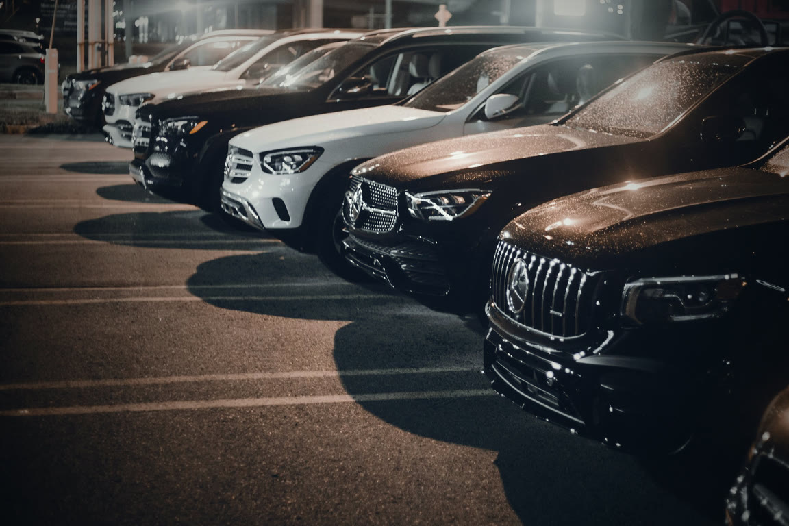 A row of vehicles parked on a lot after dark
