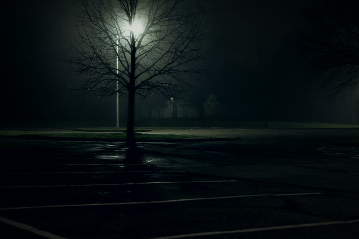 An empty lot under a single light at night