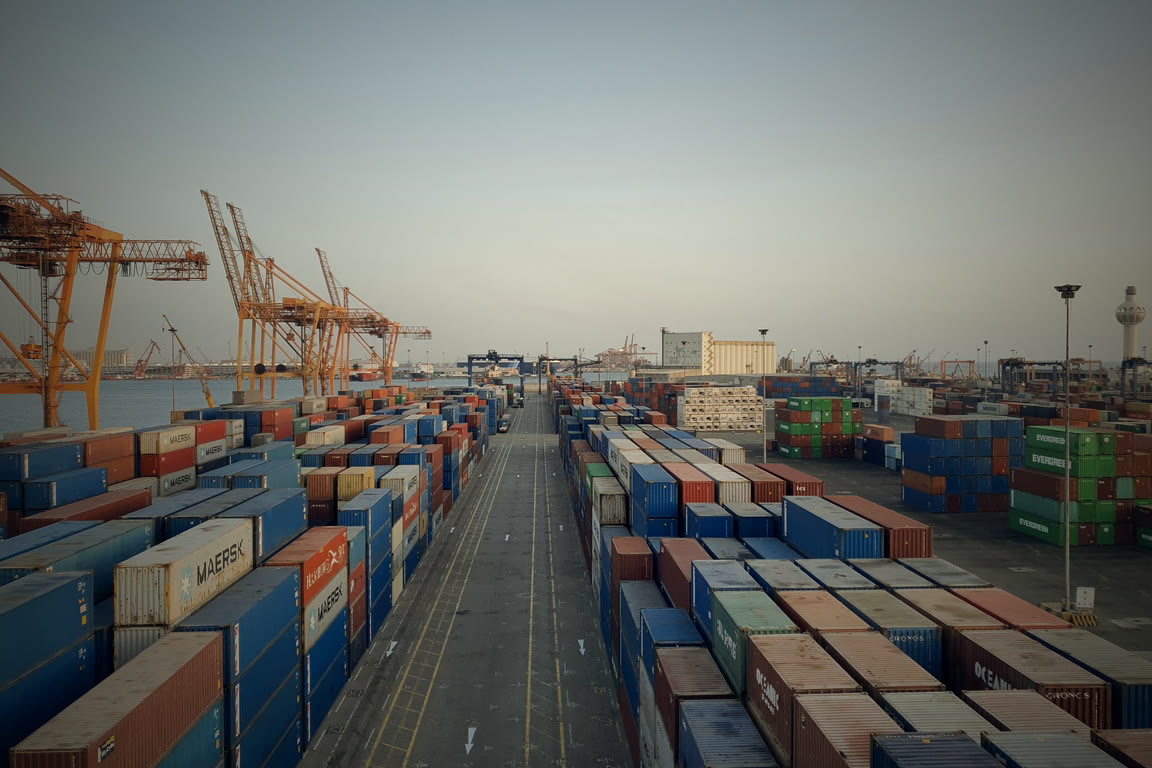 Rows of shipping containers and stock across a yard at dusk