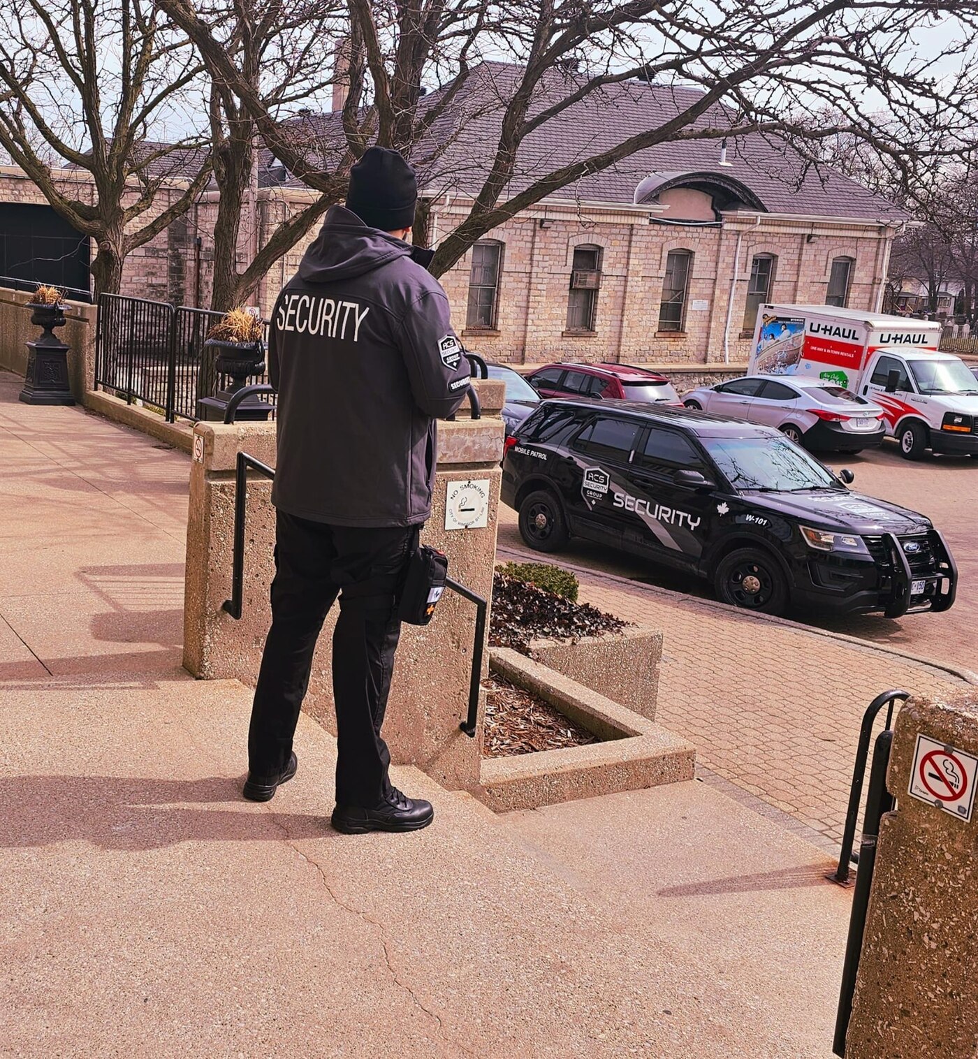 ACS security guard on post beside a marked ACS mobile patrol vehicle