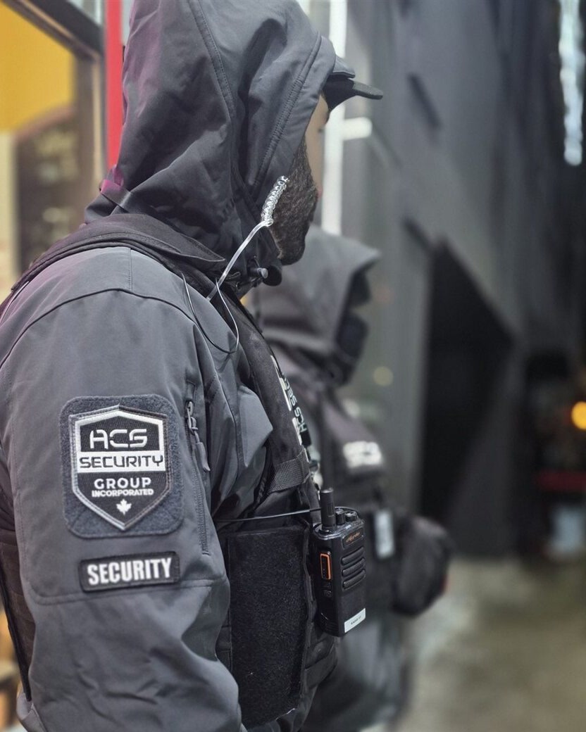 Two ACS security guards in tactical jackets on night patrol