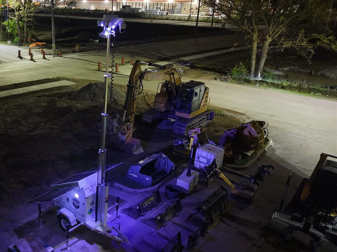 Aerial night view of an ACS solar mobile defense tower lit over an active road construction site