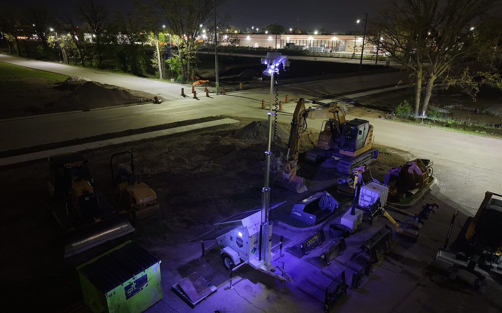 Aerial night view of an ACS solar mobile defense tower lit over an active road construction site