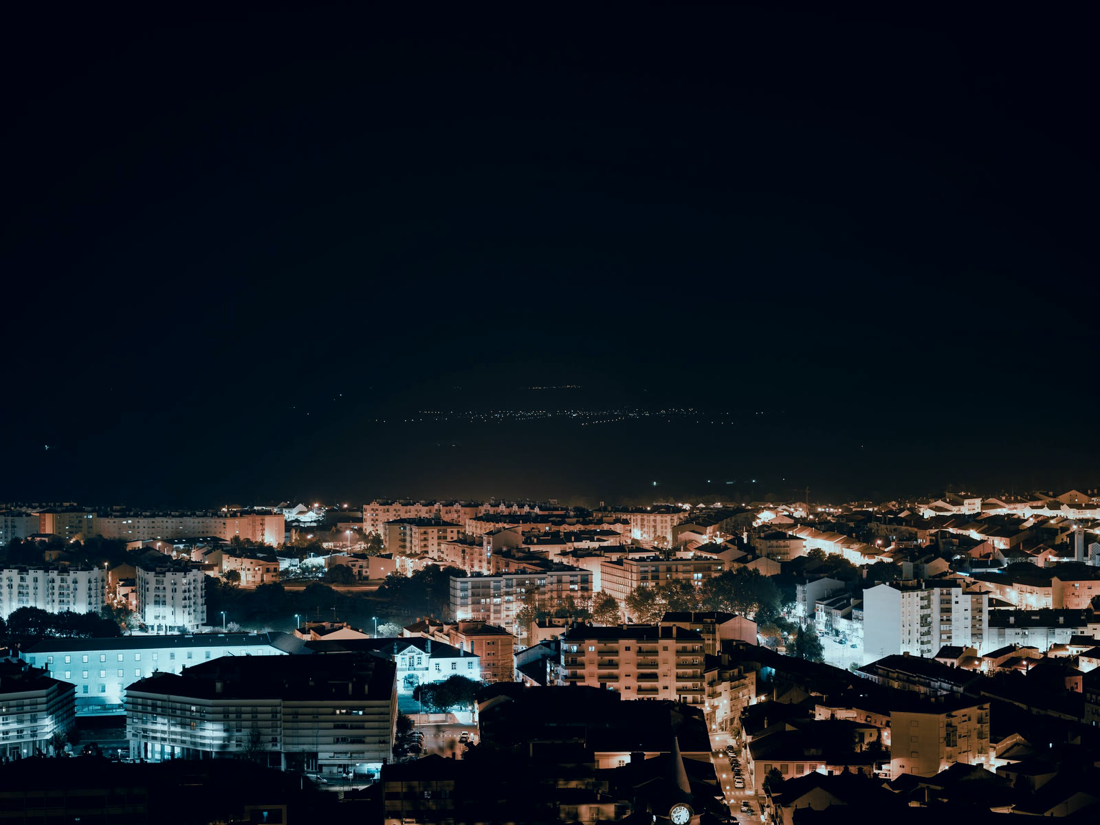 A wide view over a lit district at night, roads and buildings running into the dark