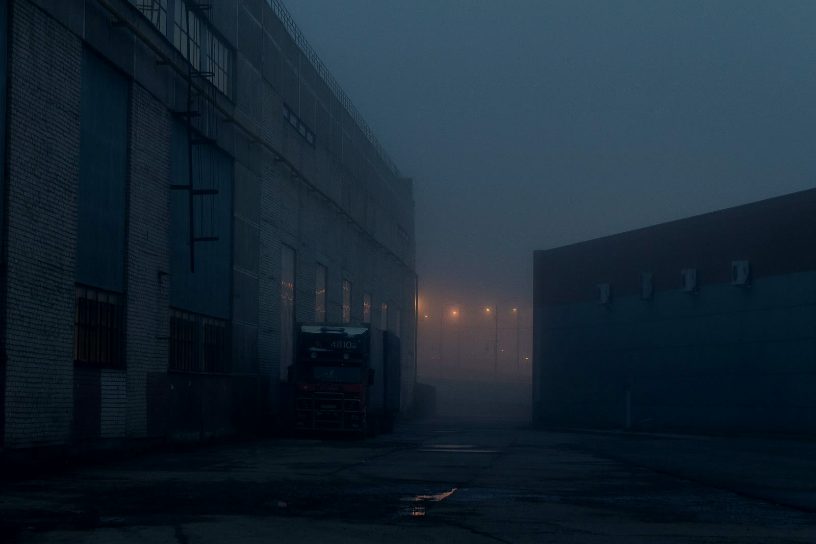 A truck beside an industrial building in heavy night fog