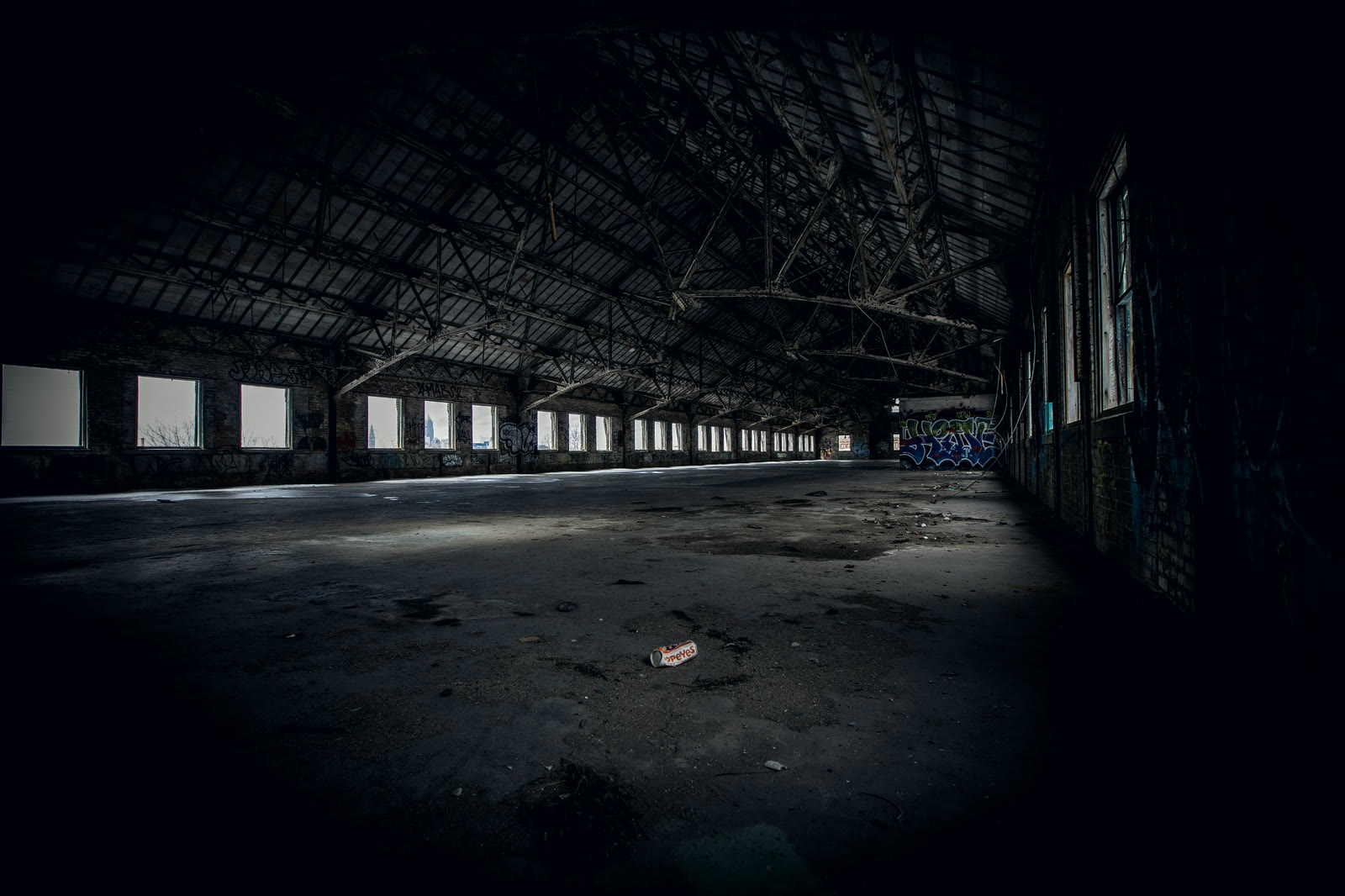 The inside of a large warehouse, lit only from the far end