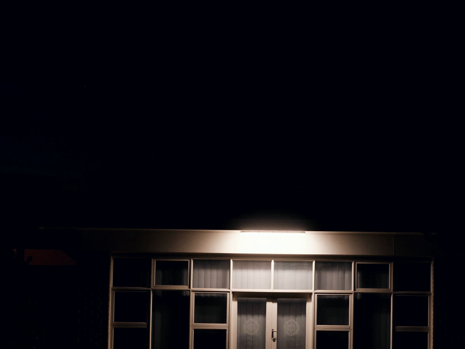 A single-storey retail unit at night, its glass front lit and nobody inside