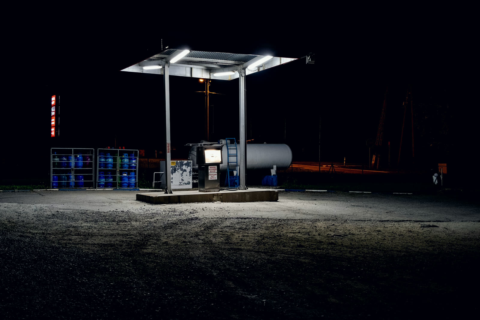 A small fuel forecourt lit at night with nobody on it