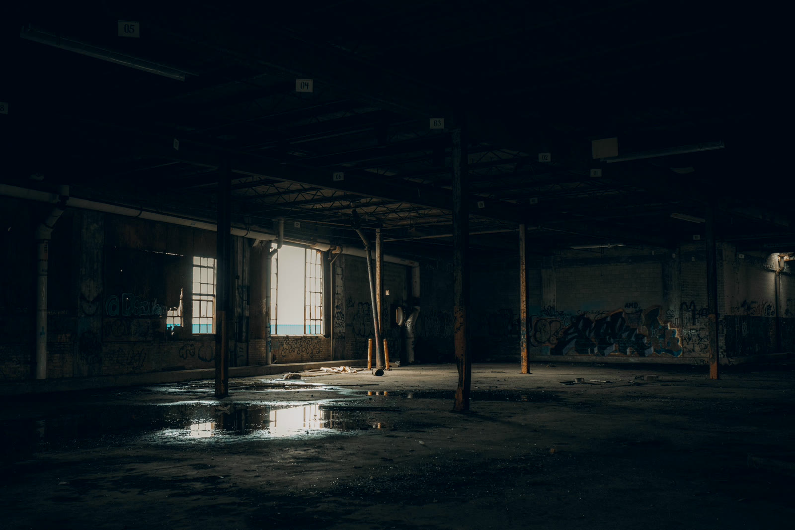 An empty industrial interior with standing water across the slab