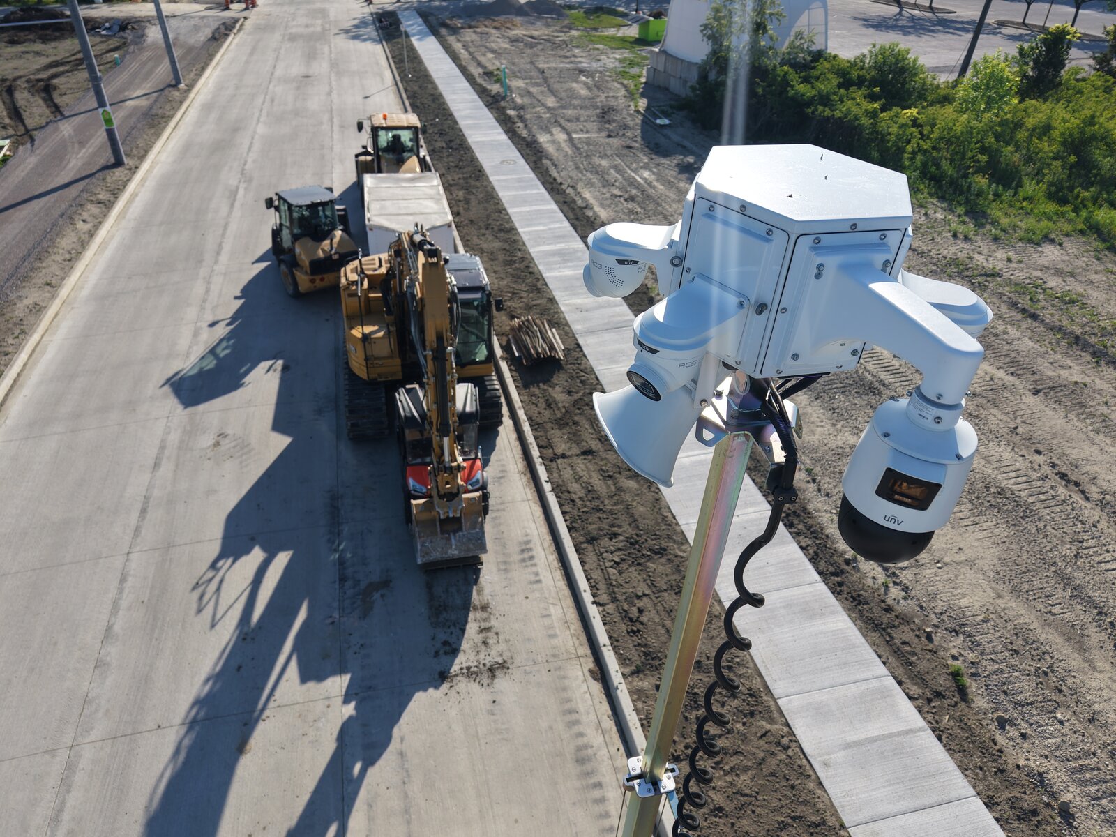 Aerial view of an ACS camera tower overlooking active excavation and paving equipment on a road build