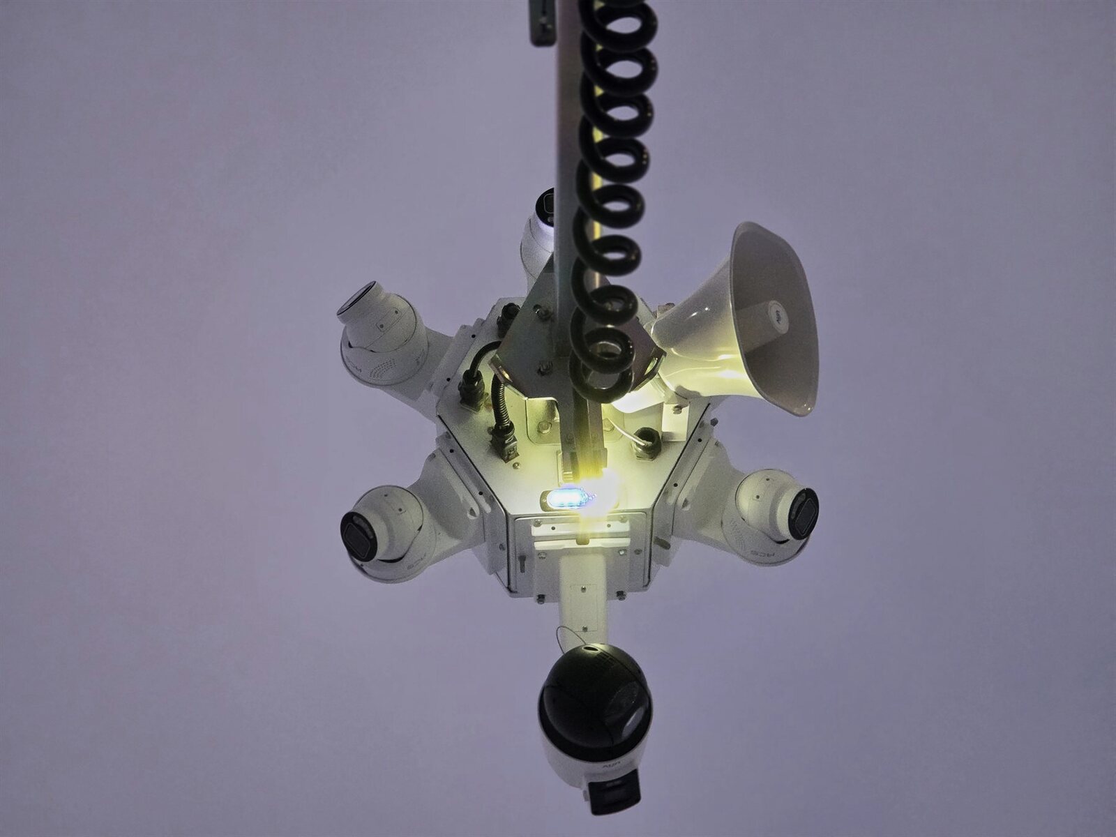 ACS tower camera head with horn speakers and a lit strobe, seen from below at dusk