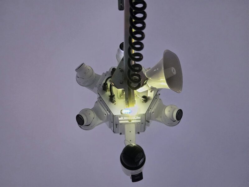 Close view of a tower camera head with lights active against the night sky