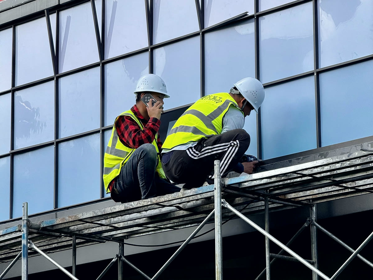 Two workers on scaffolding installing glazing into the face of a building