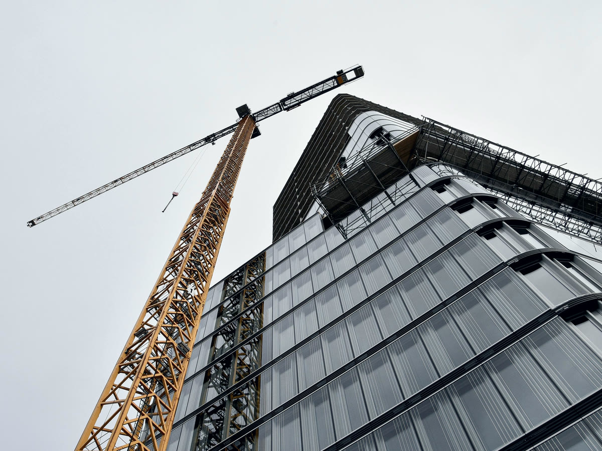 The frame of a building under construction with a crane above it