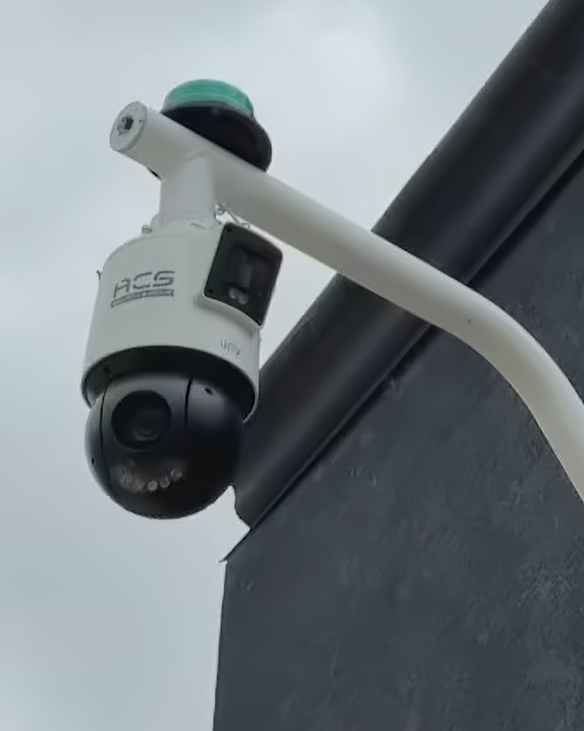 An ACS-branded pan-tilt-zoom camera and strobe mounted on the corner of a commercial building