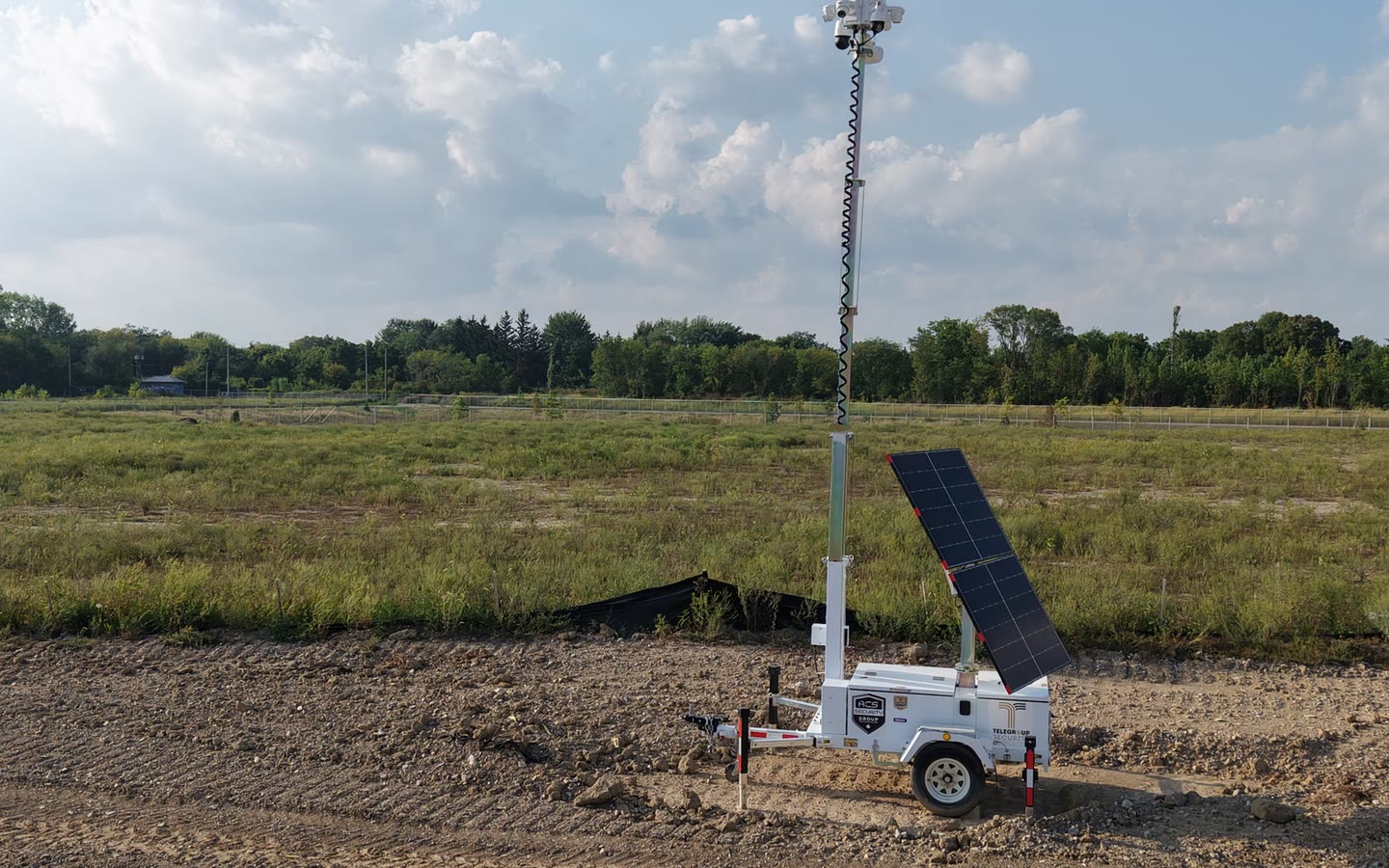 An ACS solar tower standing alone on open vacant ground, mast raised